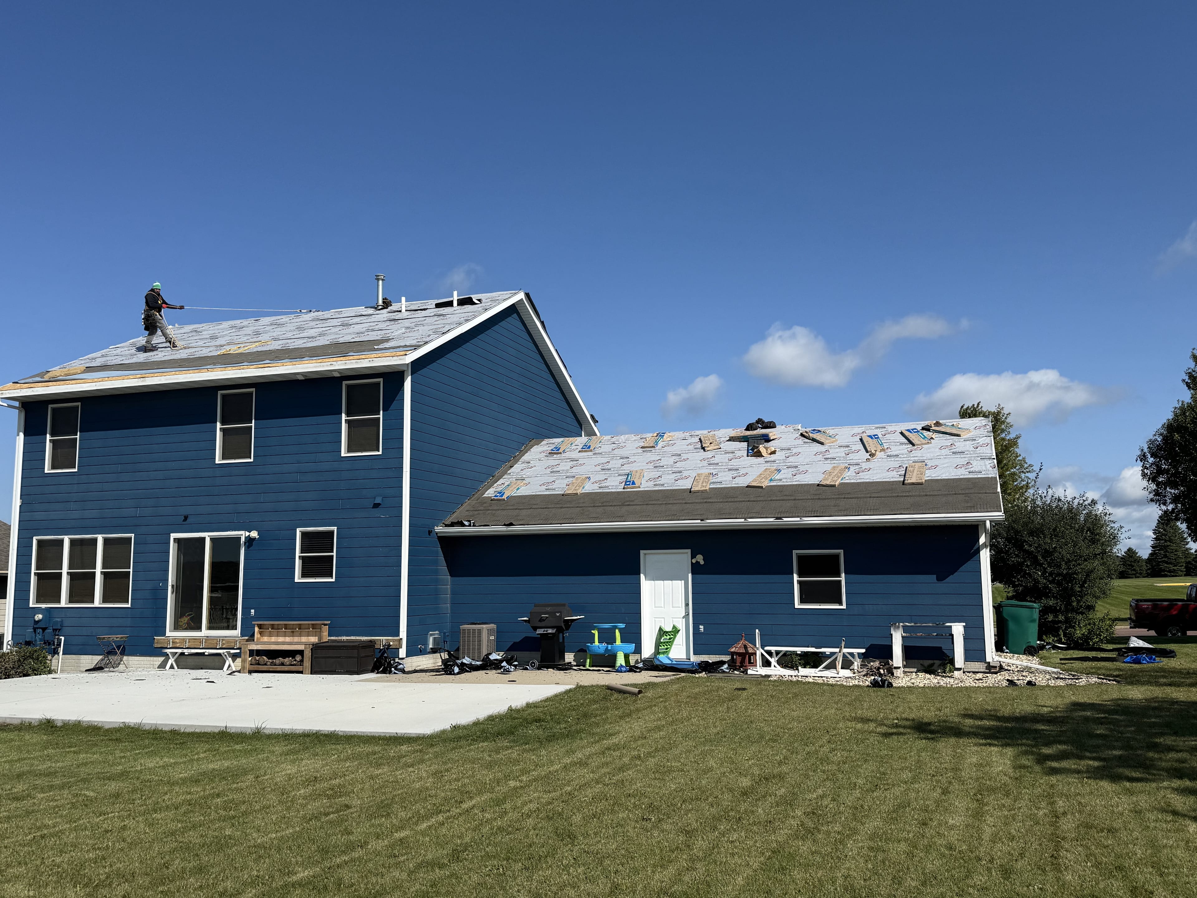 A two-story home mid-reroof, with synthetic underlayment going down over the stripped slope