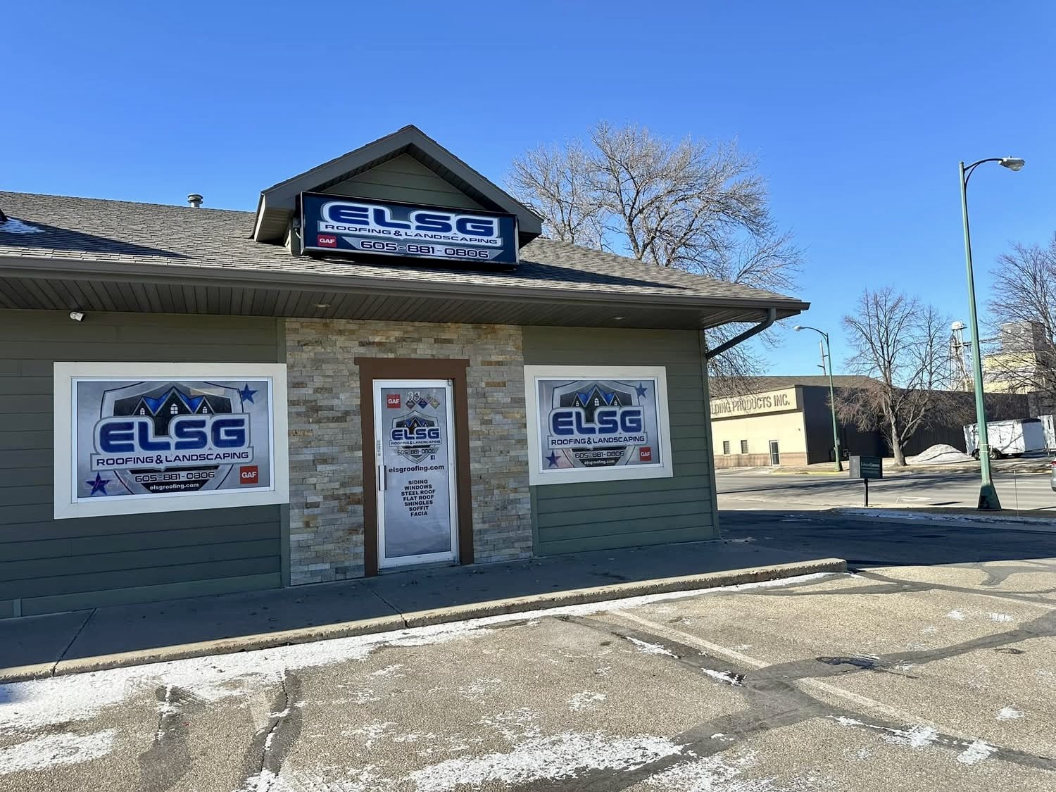 Our own storefront: the ELSG sign lit above the door, window decals on both sides, and the parking lot out front.