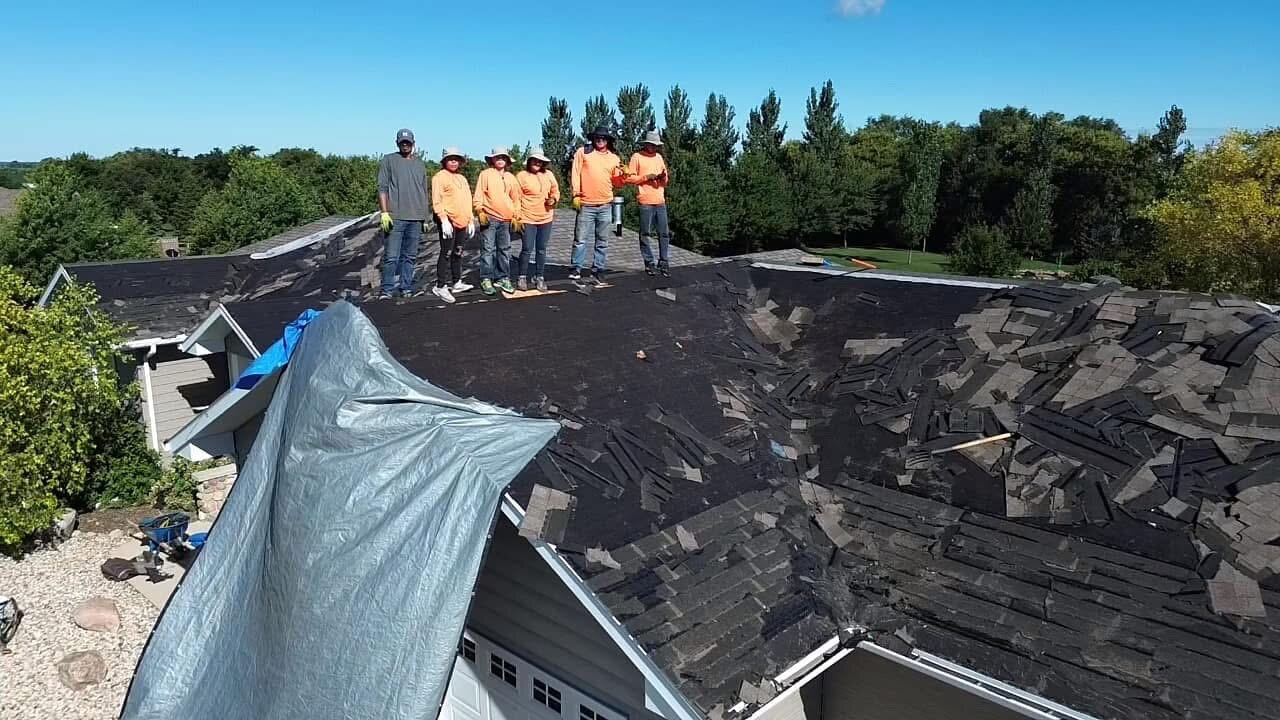 The crew on a tear-off: old shingles stripped, the whole deck opened up before the new roof goes down.